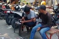 Dua juru parkir tampak menghitung uang hasil pungutan parkir di kawasan Pasar Srimangunan Sampang. Aktivitas ini menjadi sorotan di tengah polemik dugaan praktik mafia parkir. (Foto: Syaman Syah)