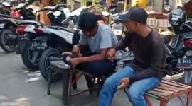 Dua juru parkir tampak menghitung uang hasil pungutan parkir di kawasan Pasar Srimangunan Sampang. Aktivitas ini menjadi sorotan di tengah polemik dugaan praktik mafia parkir. (Foto: Syaman Syah)