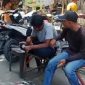 Dua juru parkir tampak menghitung uang hasil pungutan parkir di kawasan Pasar Srimangunan Sampang. Aktivitas ini menjadi sorotan di tengah polemik dugaan praktik mafia parkir. (Foto: Syaman Syah)