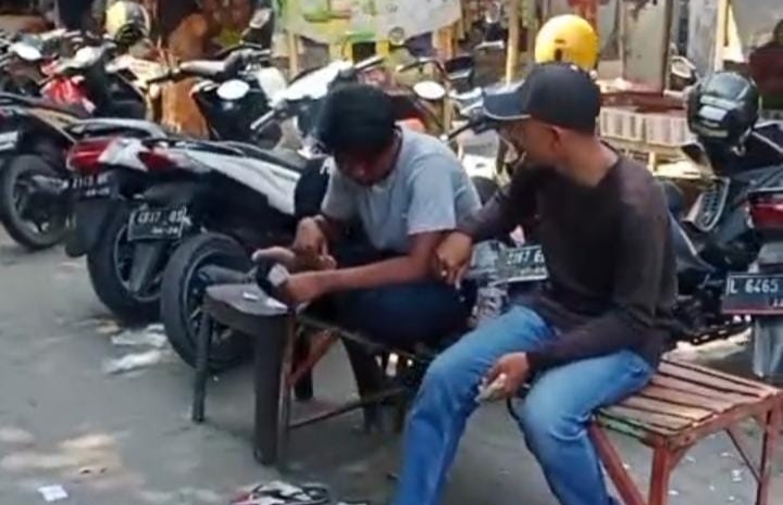 Dua juru parkir tampak menghitung uang hasil pungutan parkir di kawasan Pasar Srimangunan Sampang. Aktivitas ini menjadi sorotan di tengah polemik dugaan praktik mafia parkir. (Foto: Syaman Syah)