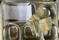 Petugas SPPG Bungsang Bangkalan menunjukkan ompreng berisi surat dan uang dari siswa sebagai bentuk ucapan terima kasih atas makanan bergizi yang mereka terima.