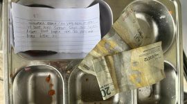 Petugas SPPG Bungsang Bangkalan menunjukkan ompreng berisi surat dan uang dari siswa sebagai bentuk ucapan terima kasih atas makanan bergizi yang mereka terima.