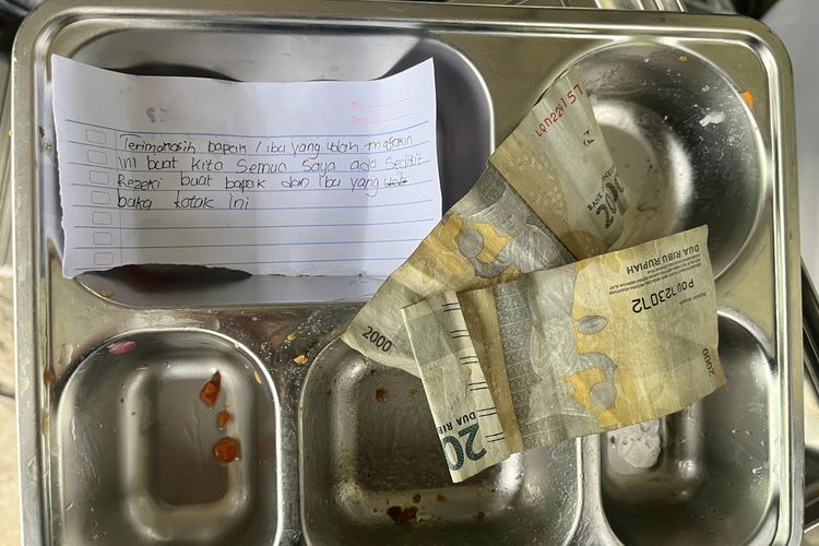 Petugas SPPG Bungsang Bangkalan menunjukkan ompreng berisi surat dan uang dari siswa sebagai bentuk ucapan terima kasih atas makanan bergizi yang mereka terima.