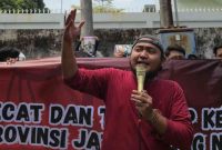 Koordinator Jaka Jatim, Musfiq (tengah), memimpin aksi unjuk rasa di depan Kantor Dinas PRKPCK Provinsi Jawa Timur, Selasa (26/11/2025). Massa menuntut KPK segera mengusut dugaan korupsi dana hibah senilai Rp249 miliar.