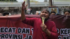 Koordinator Jaka Jatim, Musfiq (tengah), memimpin aksi unjuk rasa di depan Kantor Dinas PRKPCK Provinsi Jawa Timur, Selasa (26/11/2025). Massa menuntut KPK segera mengusut dugaan korupsi dana hibah senilai Rp249 miliar.