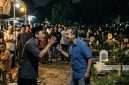 ilustrasi dua orang Cekcok di Tengah Acara Warga di area pemakaman pada saat malam hari.